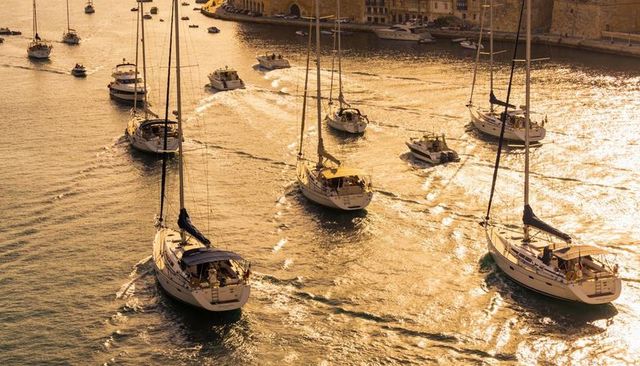 Yachts gliding through harbor at golden hour sunlight