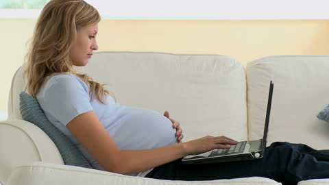 Pregnant Woman Using Laptop Relaxing on Sofa