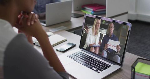 Woman watching business presentation on laptop in office setting