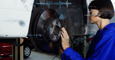 Female technician inspecting brake rotor using augmented reality diagnostics in garage