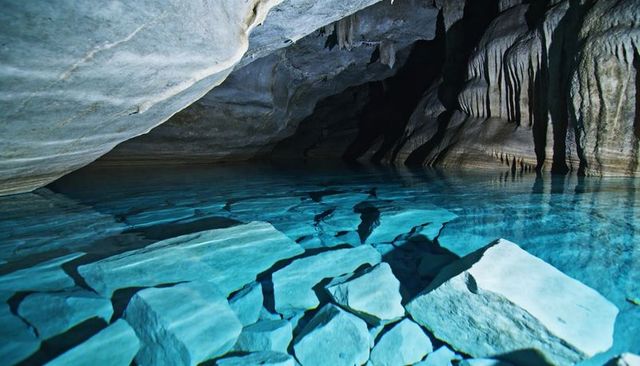 Turquoise Cave Pool Revealing Submerged Limestone Slabs and Flowstone Reflections