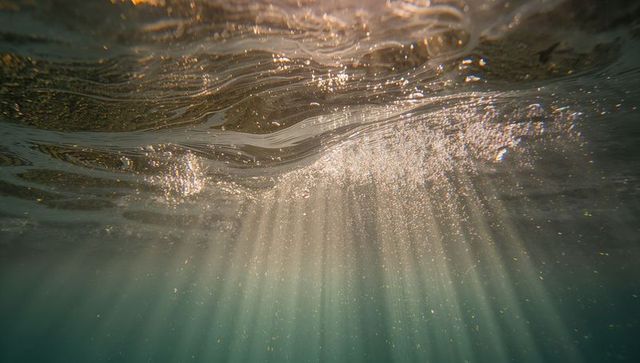 Sunbeams submerging through tranquil ocean water with suspended particles