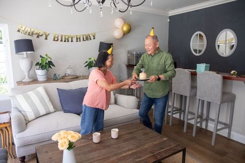Senior asian couple celebrating home birthday with cake, balloons and pastel gold decor