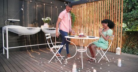 Romantic Candlelit Dinner Outdoors with Diverse Couple Seated at Table