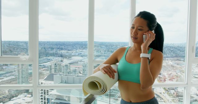 Fitness Woman Talking on Phone Holding Yoga Mat in Bright City Apartment - Download Free Stock Images Pikwizard.com