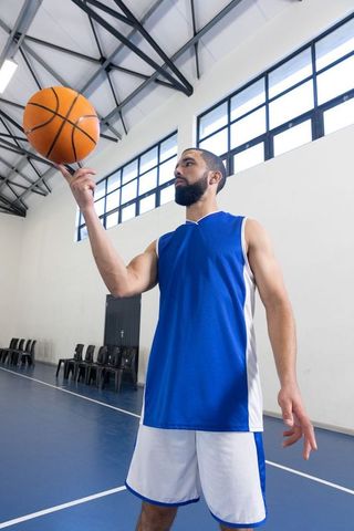 African american athlete spinning basketball in gym