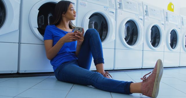 Young Woman Relaxing in Laundromat Using Smartphone - Download Free Stock Images Pikwizard.com