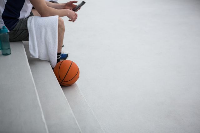 Basketball player using mobile phone on terrace