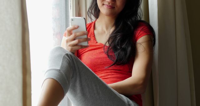 Young Woman Relaxing by Window Using Smartphone - Download Free Stock Images Pikwizard.com