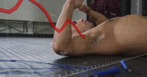 Lying shirtless athlete resting on gym mat with descending red chart overlay, fatigue