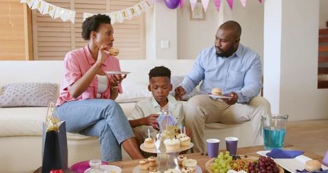 African American Family Celebrating Son's Birthday at Home with Cupcakes Balloons Gifts
