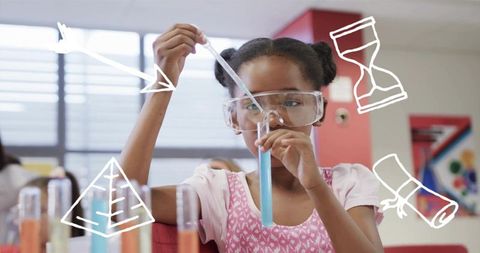 Elementary student pipetting blue solution in classroom science lab wearing safety goggles