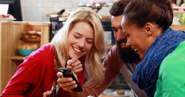 Friends Enjoying Laughs Over Smartphone in Cozy Cafe - Download Free Stock Images Pikwizard.com