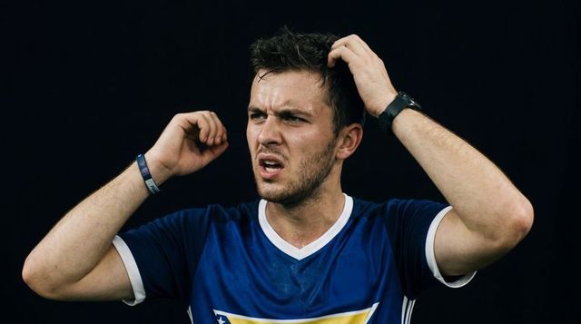 Athlete touching head and ear, showing frustration and confusion in dark studio