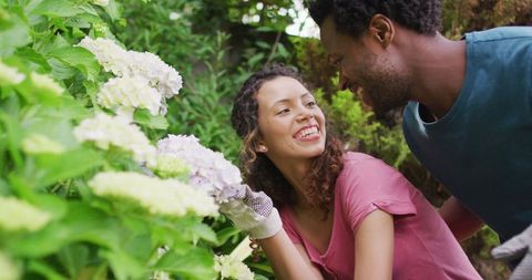Biracial couple joyfully gardening together among flowers