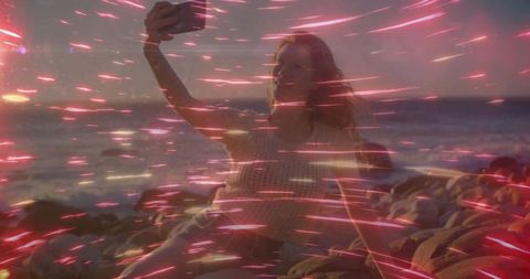 Capturing sunset: selfie on rocky ocean shore with vibrant light trails