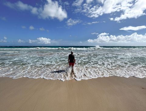 Solitary Figure Facing Ocean on Sunny Beach