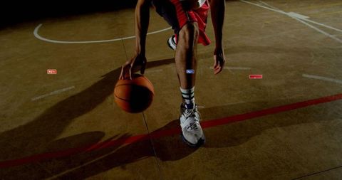 Basketball player dribbling on indoor court casting dramatic shadow