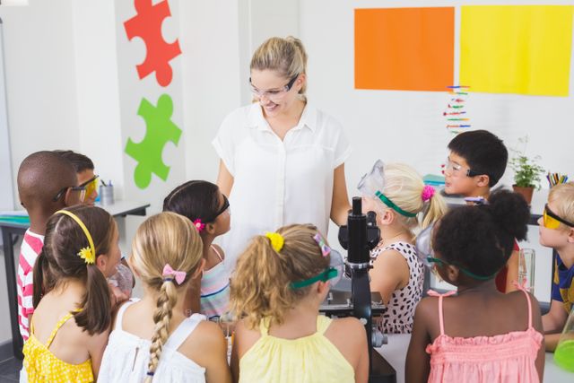 Teacher guiding diverse group of children in science lab, all wearing safety goggles. Ideal for educational content, school brochures, STEM programs, and promoting science education among young students.
