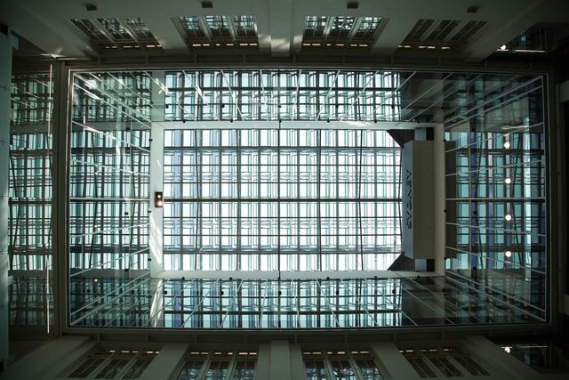 Looking up at skylight ceiling showcasing advanced structural design in modern building with geometric glass patterns and natural light. Ideal for articles on architecture, structural engineering concepts, or contemporary design trends.