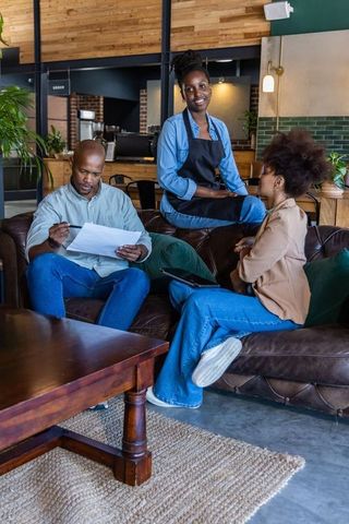 African coworkers reviewing documents in coffeehouse lounge for team collaboration