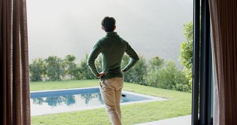 Melancholic Man Overlooking Tranquil Pool and Greenery in Modern Setting