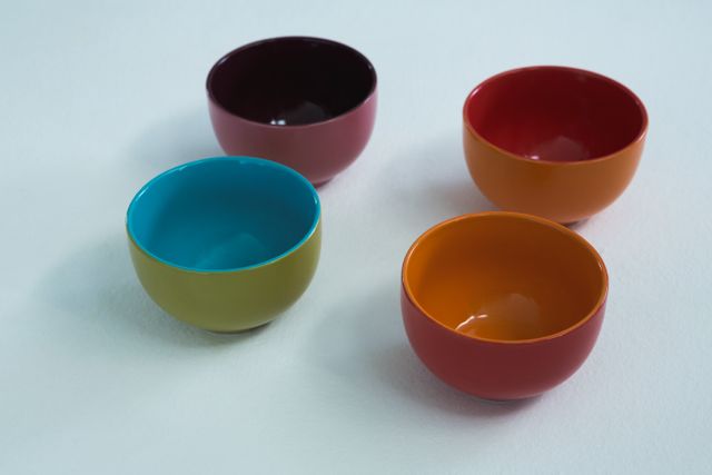 This image features four colorful empty bowls arranged on a white background. The vibrant colors and minimalist design make it ideal for use in kitchenware advertisements, home decor blogs, or modern dining presentations. It can also be used to highlight food presentation ideas or for promoting ceramic products.