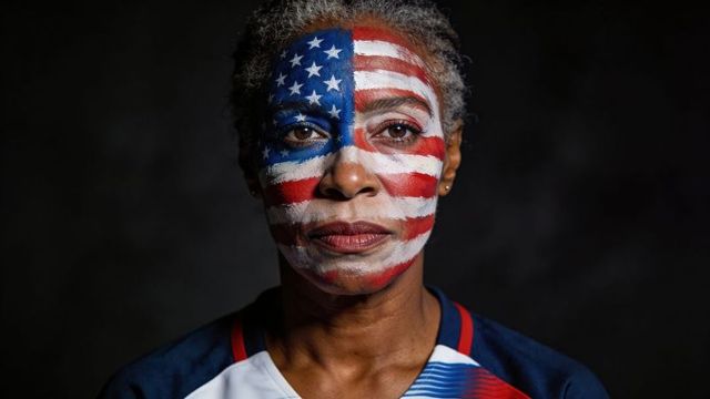 Senior woman wearing full-face us flag paint portrait conveying patriotism and resilience