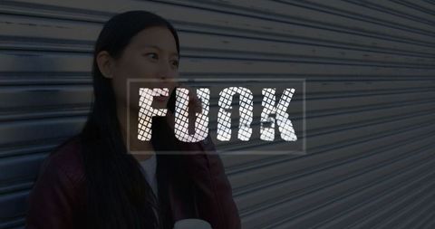 Woman with coffee on phone near storefront metal shutter