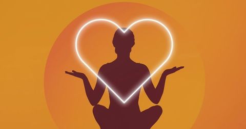 Silhouette meditating with glowing heart motif