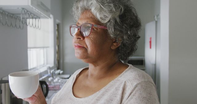 Senior Woman with Coffee in Cozy Kitchen Gazing Outside - Download Free Stock Images Pikwizard.com