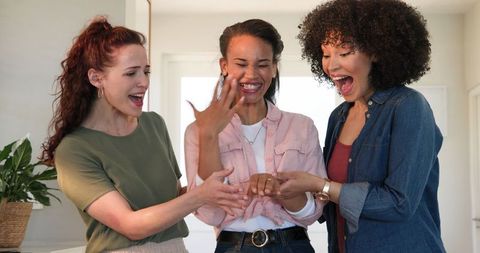 Joyful friends celebrating engagement in bright kitchen