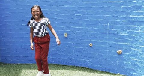 Joyful Girl Playing Outside by Blue Wall