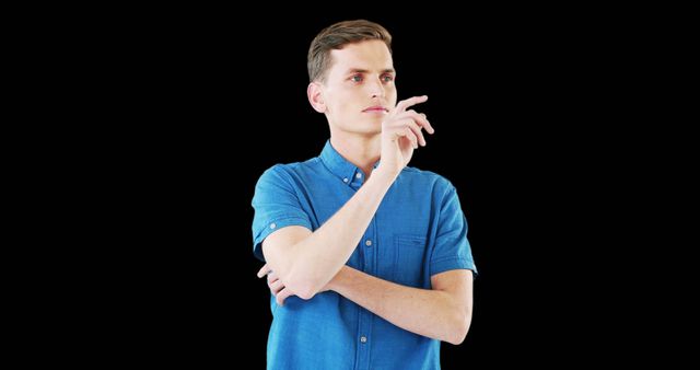 A young man, dressed casually in a denim shirt, appearing deep in thought against a black background. This can be used in advertisements, blogs, or mental health resources to signify contemplation, introspection, or decision-making.