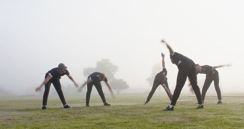 Male Athletes Stretching in Foggy Park for Wellness and Fitness