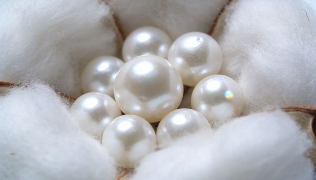 Pearl cluster nestling in cotton boll macro closeup lustrous nacre luxury concept