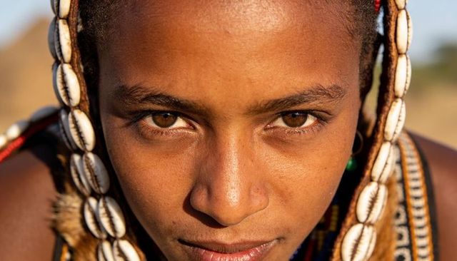 East african teen gazing in golden light wearing cowrie shells and beaded necklaces
