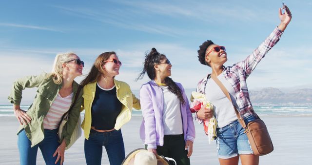 Happy group of diverse female friends having fun, taking selfie with smartphone at the beach. holiday, freedom and leisure time outdoors.