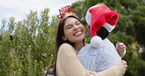 Friends hugging outdoors wearing santa hat and merry christmas headband celebrating friendship