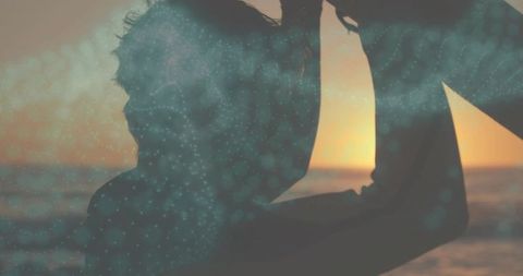 Father holding infant silhouette at coastal sunset with teal digital overlay