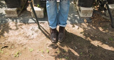 Gardener in Rolled-Up Jeans Standing at Plant Nursery