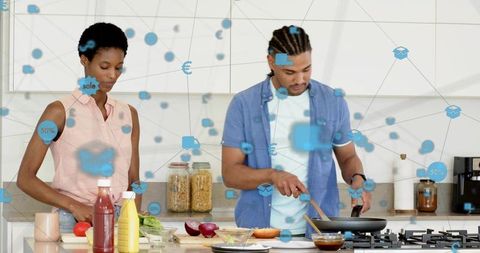 Couple cooking healthy meal in modern kitchen with smart-home data overlay