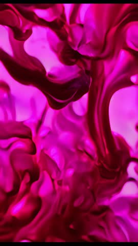 Vertical video of magenta pigment forming twisting plumes and tendrils in clear beaker
