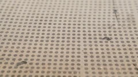 Shifting Camera Sliding Over Beige Perforated Panel Revealing Dot Grid, Seam, Macro Motion