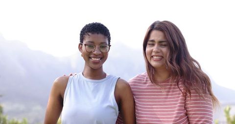 African american woman and friend smiling and embracing on scenic mountain overlook