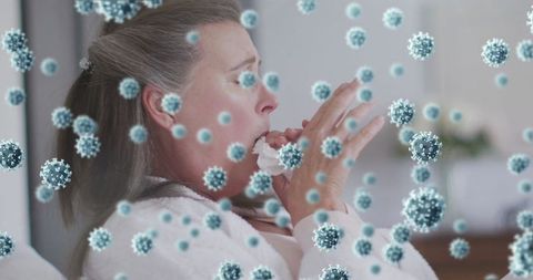 Mature woman sneezing indoors amidst floating virus particles