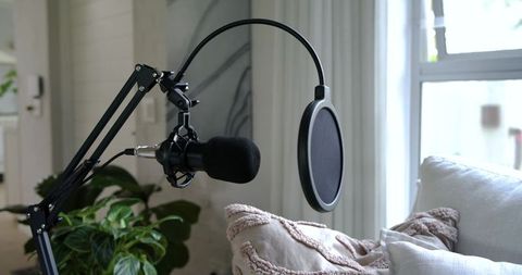 Podcast microphone recording setup on boom arm in cozy living room