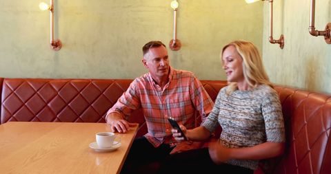 Casual conversation at diner with matching attire and smartphone
