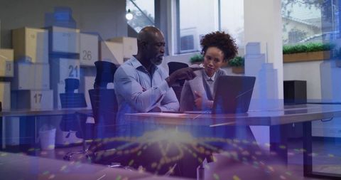 Senior mentor guiding junior colleague through data visualization on laptop in office