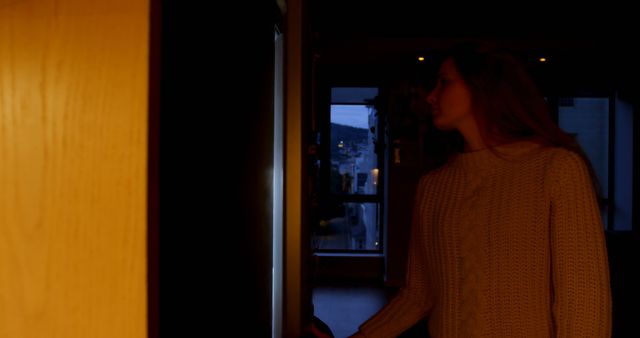 Woman in Warm Sweater Entering Dimly Lit Room at Dusk - Download Free Stock Images Pikwizard.com